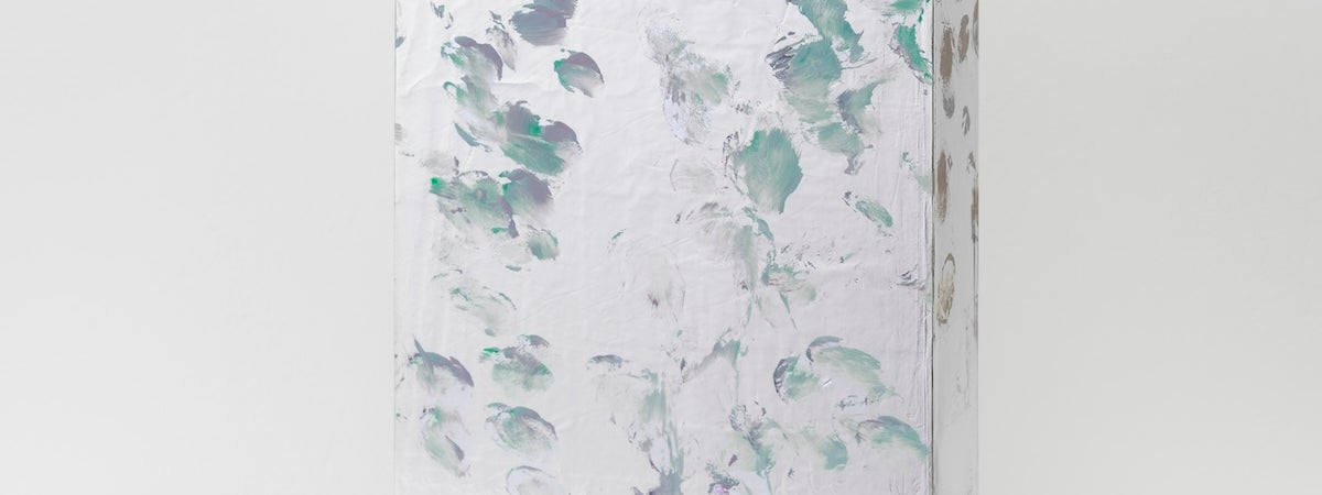 A photo of a small free-standing painting with green and purple daubled brush marks on a silver surface