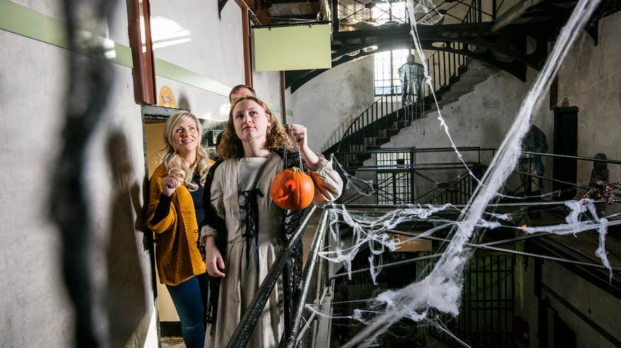 Three people on a Halloween tour through Wicklow Gaol.