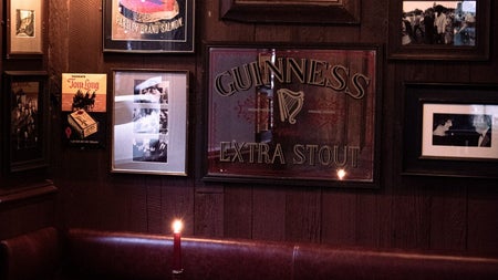 Dark interior of a pub with pictures on the walls and a bottle with a lighting candle on a table