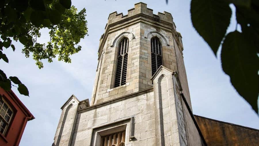 Ground level view of a church next to a red building with trees in the top corners