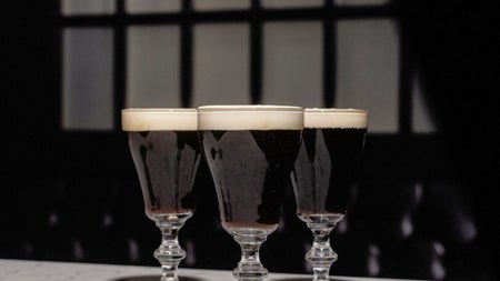 Three Irish coffee glasses sit on the corner of a white marble bar counter