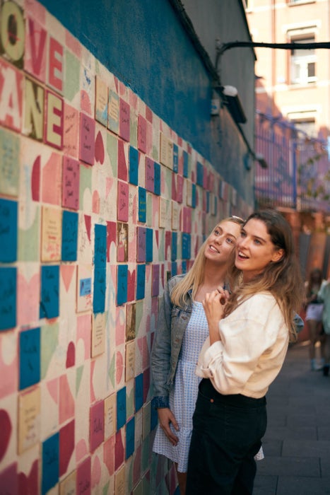Two women looking at the wall art on Love Lane in Temple Bar
