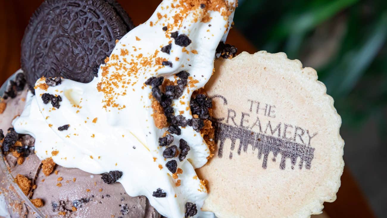 A selection of ice cream in a bowl decorated with nuts and a wafer with the café name on it