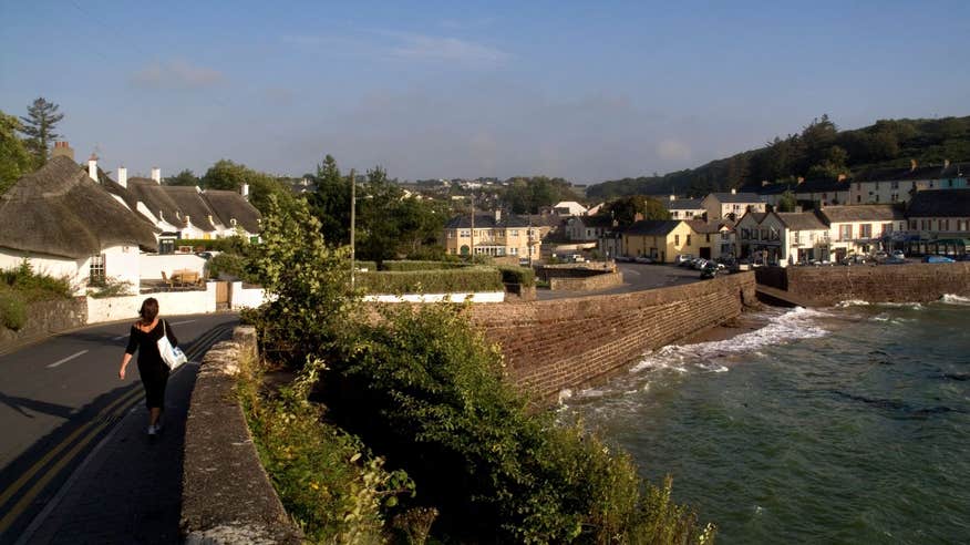 Woman walking on a country road beside the sea in Dunmore East, Waterford