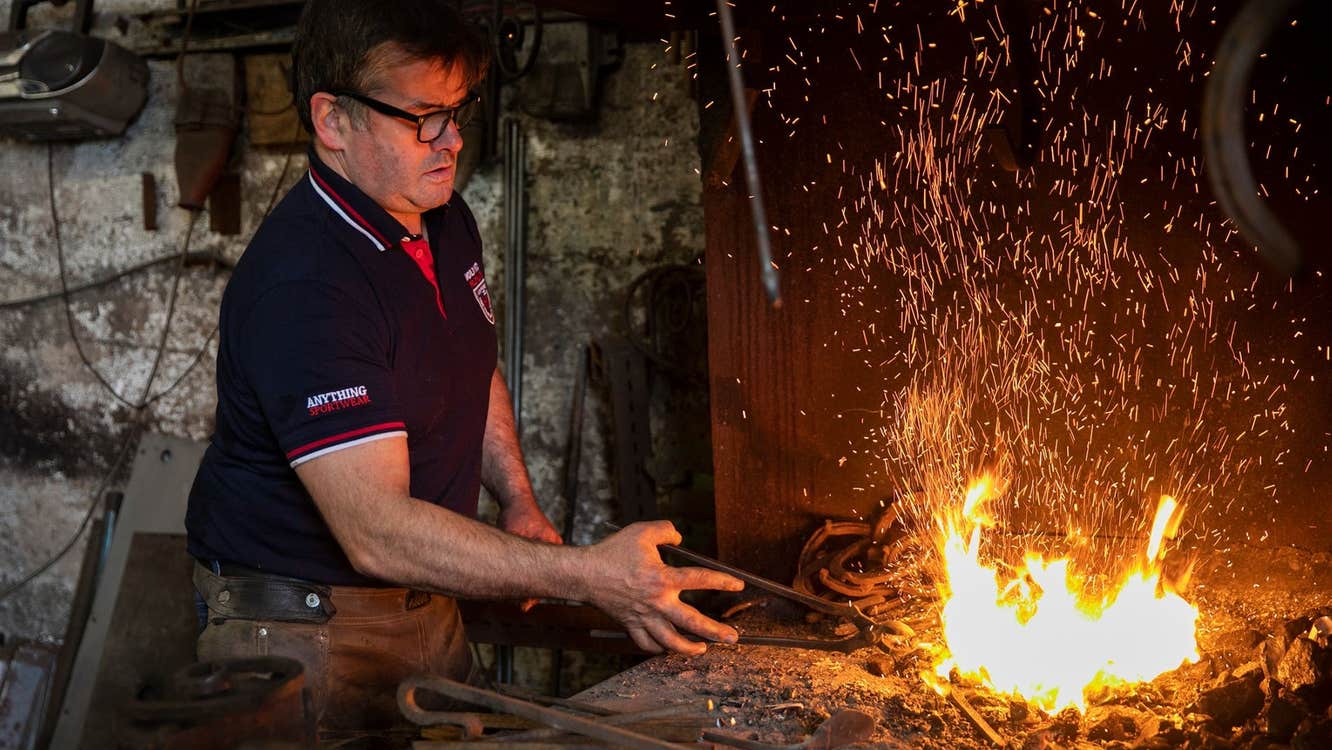 A farrier with a horseshoe heating among the flames