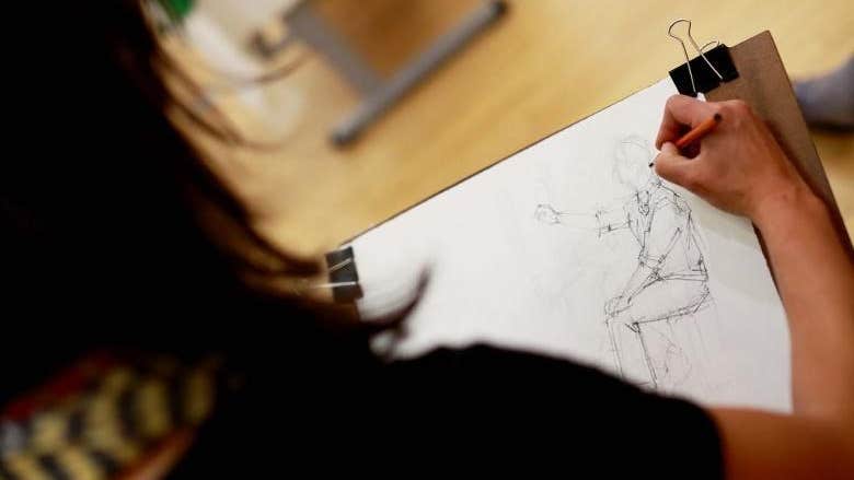 Photo © DK Photo. National Gallery of Ireland. Looking over the shoulder of a someone sketching a figure on a white piece of paper.