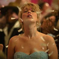 A woman in a dress with her eyes closed. She is at a party and confetti is falling.