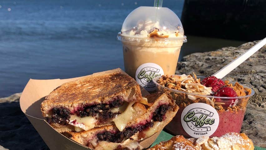 A smoothie, pastry and dessert sitting on a stone wall at Coffee Cottage
