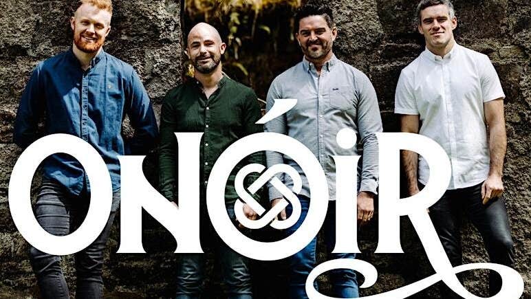 Contemporary Irish folk group Onóir, group of 4 smiling men standing in front of dark stone wall.