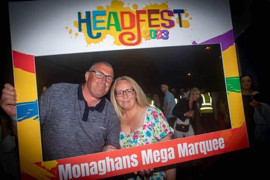 A man and woman smiling, posing in a selfie surround at 2023 Headfest at night.
