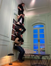 An illusion at the museum appears as a group of friends sitting on each others shoulders reaching the ceiling