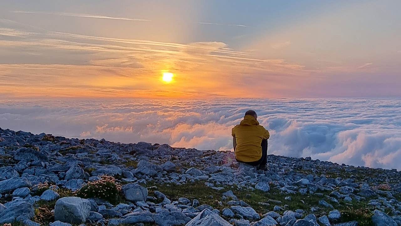 A man sitting watching a sunset while on a night hike with Tonnta Adventure