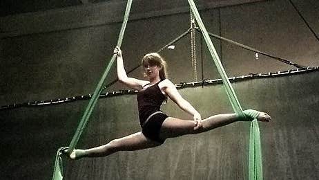 Aerial Silks practice at IADF, a woman is doing the splits up in the air hanging by the feet from long material.