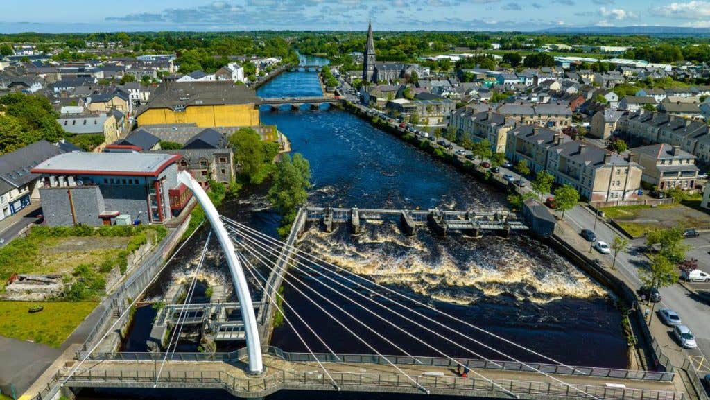 Ariel view of a town with river and modern bridge in the foreground.