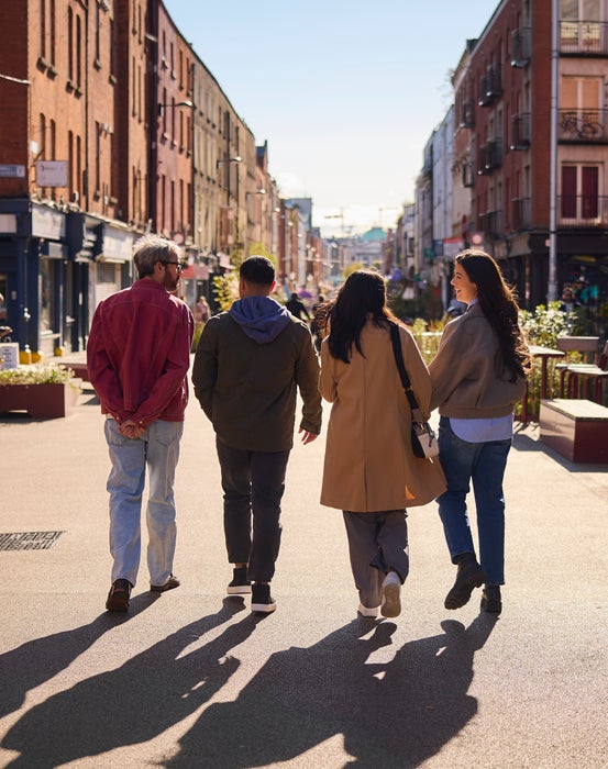 Friends walking down Capel Street in Dublin during the day.