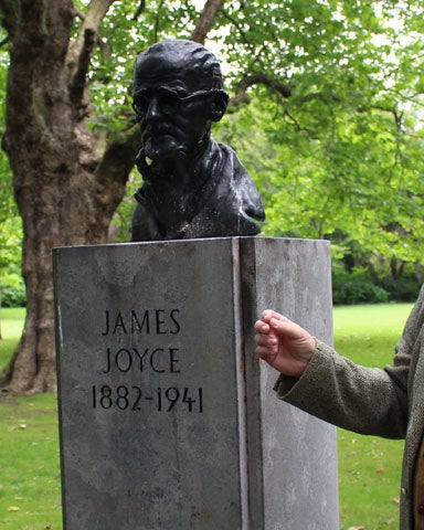A man standing next to the bust of James Joyce facing Newman House in St Stephens Green