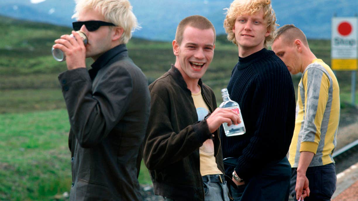 Four men drinking alcohol at the side of a road.