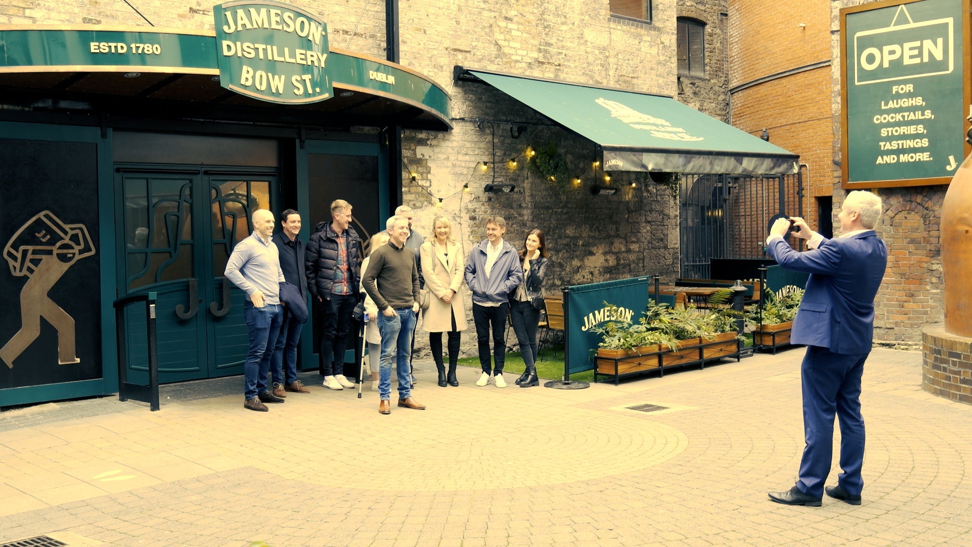 A guide takes a picture of a group of people outside the Jameson Bow Street Distillery in Dublin