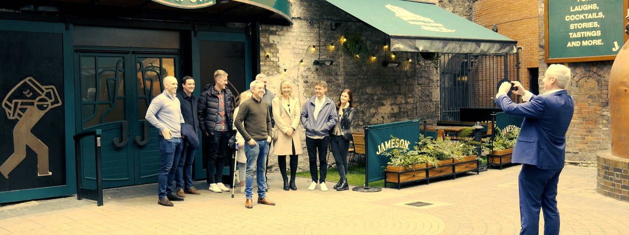 A guide takes a picture of a group of people outside the Jameson Bow Street Distillery in Dublin