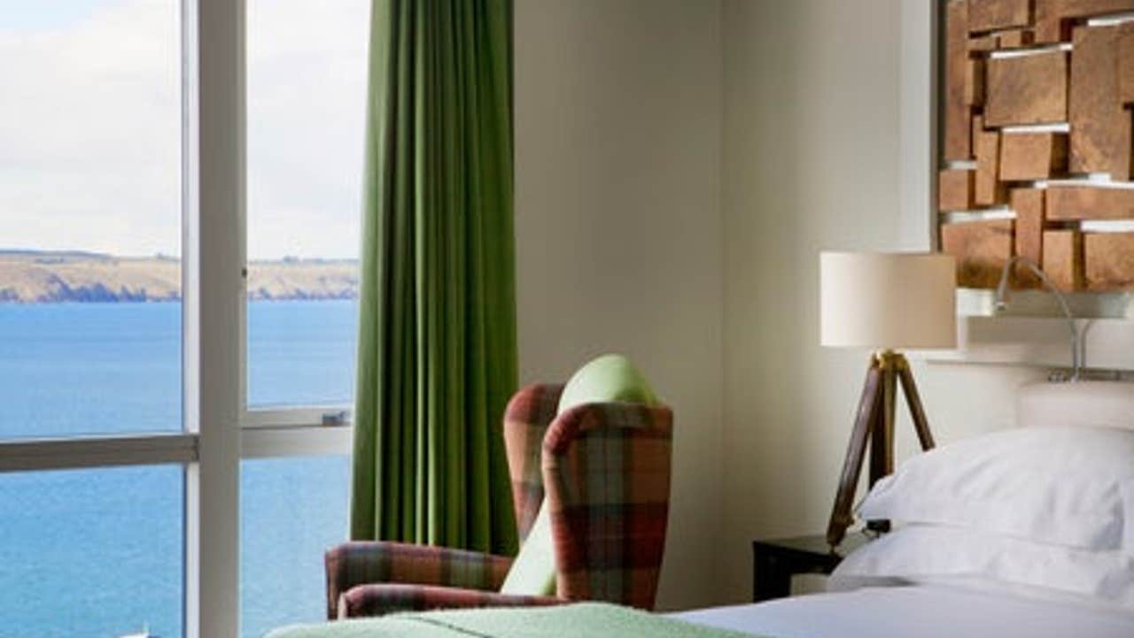 Bedroom with white linen and green throw.