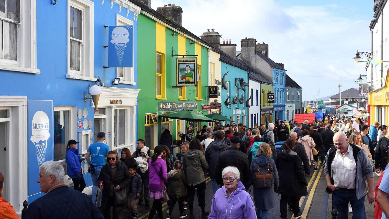 A narrow street lined by colourful, terraced buildings, full of people