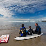 Family at the beach in West Cork with surfboards
