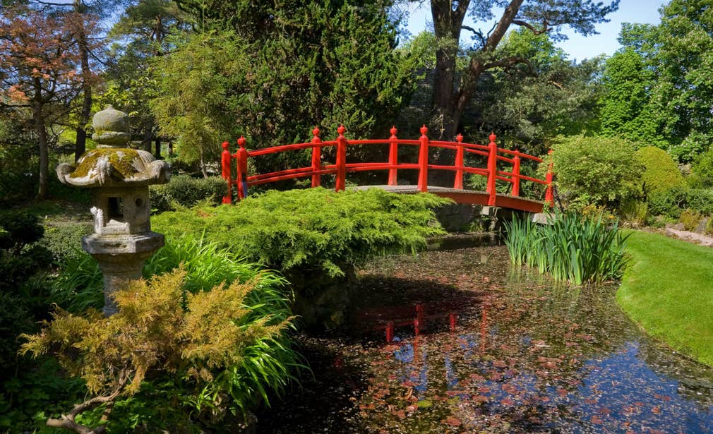 A red bridge across a pond in a beautiful garden at the Irish National Stud and Gardens in County Kildare.