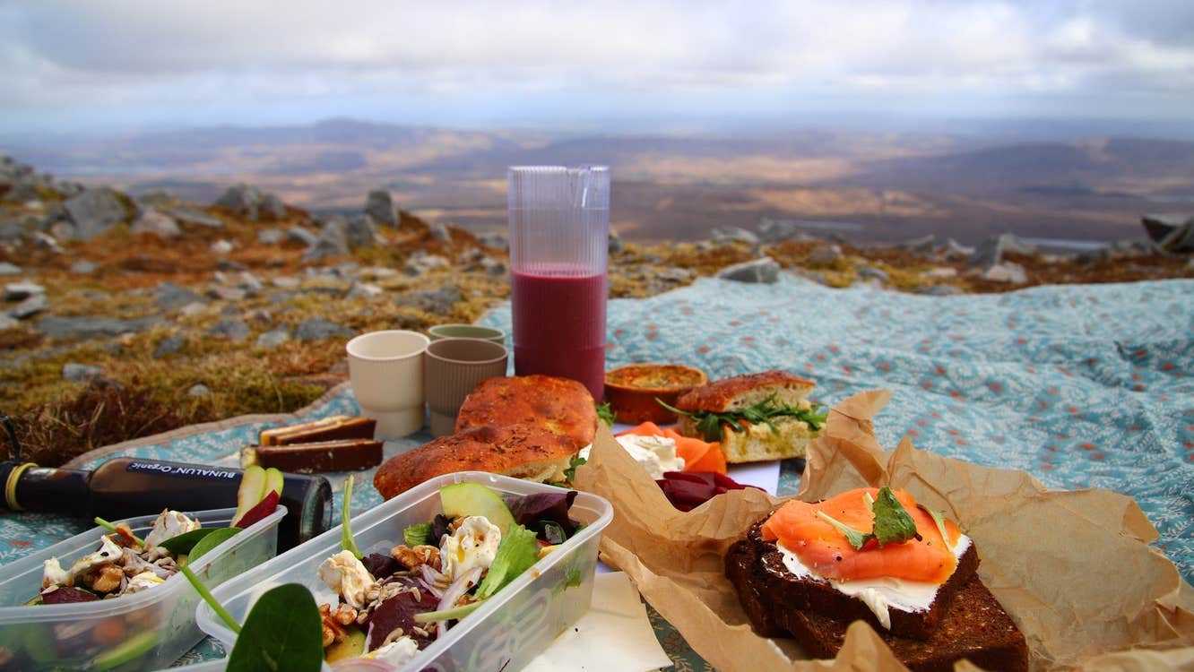 A picnic laid out on a blue blanket with mountains in the background