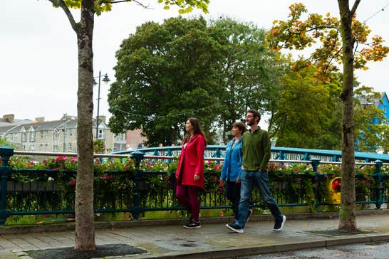Three people walking on a footpath in Sligo Town.