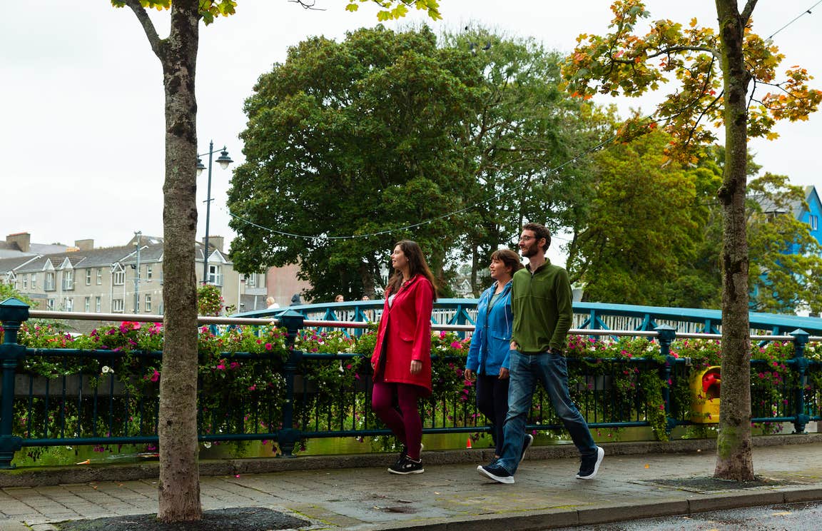 Three people walking on a footpath in Sligo Town.