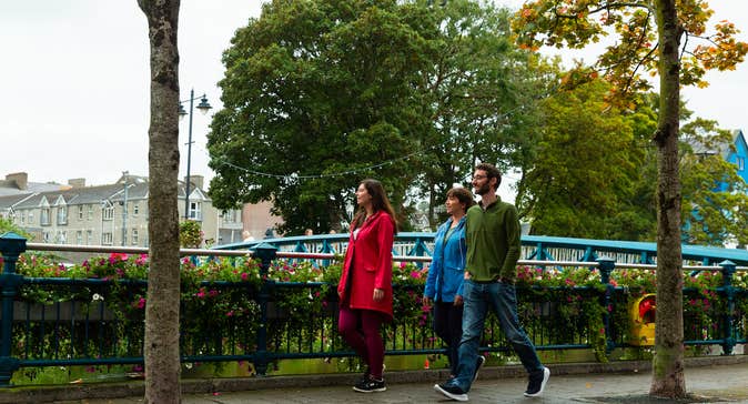 Three people walking on a footpath in Sligo Town.