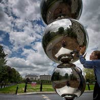 A girl looks at her reflection in the Atoms & Apples sculpture at Trinity College