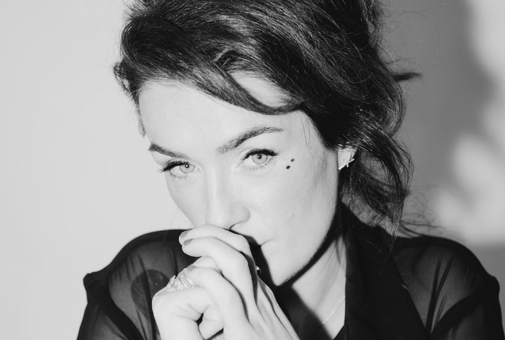 Black and white photo of woman holding hands up to mouth, looking thoughtful