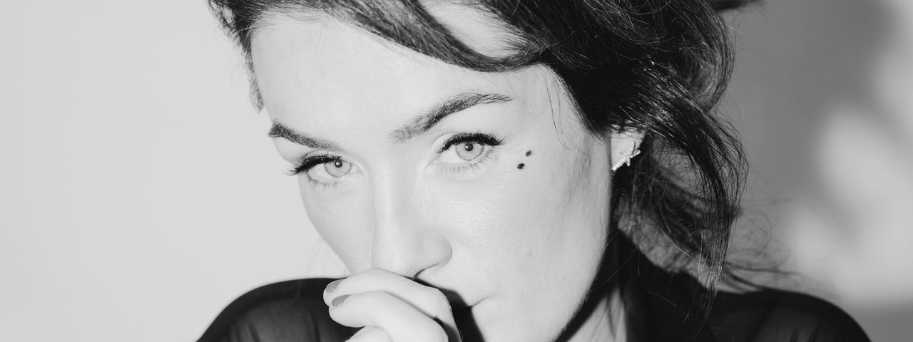 Black and white photo of woman holding hands up to mouth, looking thoughtful