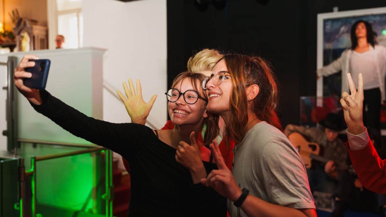 Two ladies take a selfie with a wax effigy of Michael Jackson blurred in the background