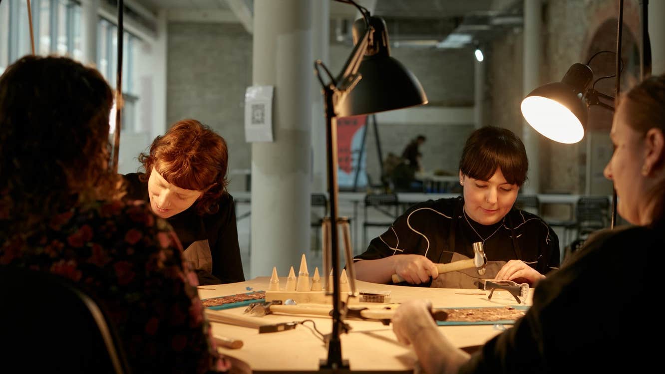 A group of people enjoying a wood working class with benchspace