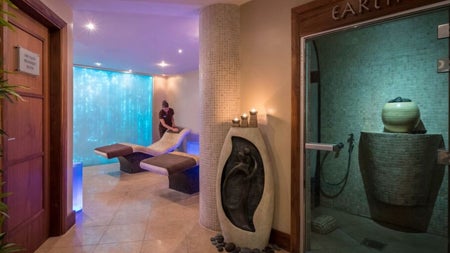 Massage therapist neatening a treatment bed in a spa room
