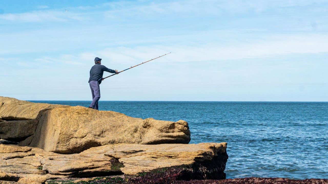 Angler casting a rod from rocks