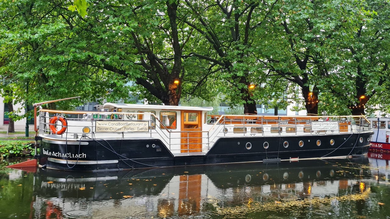 Canal barge moored on a tree lined section of a canal