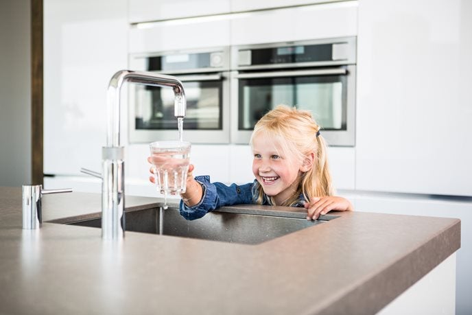 Meisje houdt glas onder de kraan