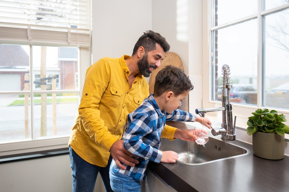 Man en kind vullen glas water aan het aanrecht