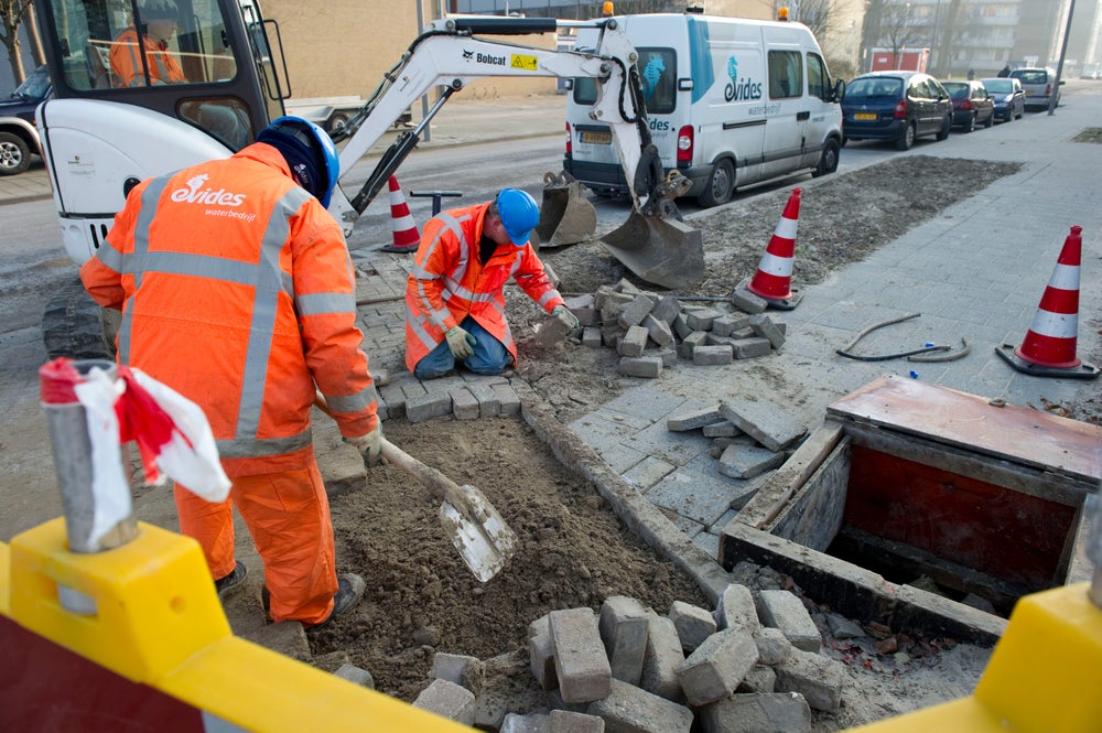 Twee monteurs zijn aan het werk in een woonwijk.