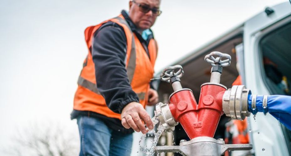 man in oranje hesje bij waterkraan