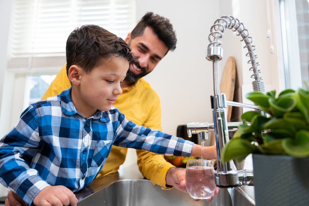 Man en kind vullen glas water.