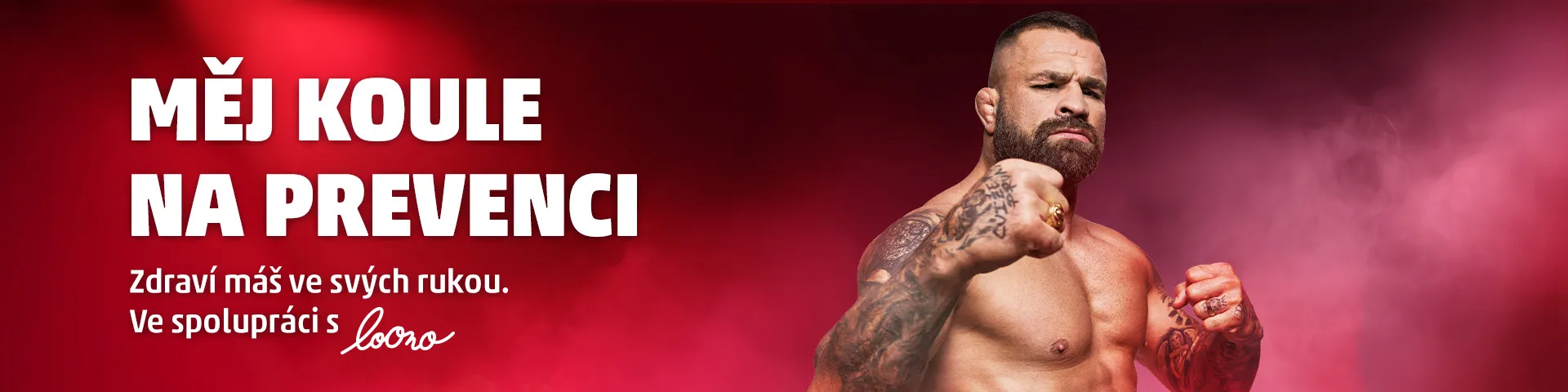Banner s Karlosem Vémolou, profesionálním zápasníkem, který ukazuje své silné ruce a vyzývá k prevenci zdraví. Pozadí je zahaleno do tmavě červené barvy s jemným kouřovým efektem, což dodává dramatický dojem. Text na banneru: 'MĚJ KOULE NA PREVENCI. Zdraví máš ve svých rukou. Ve spolupráci s Loono.