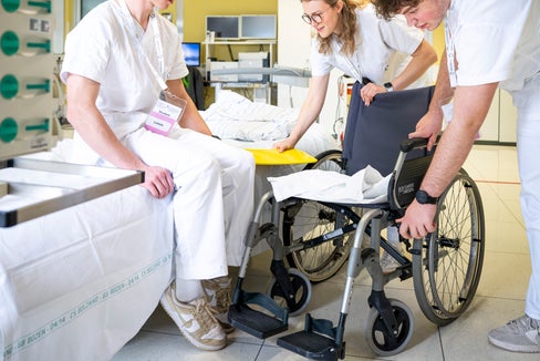 Sieht einfacher aus, als es ist: Manuel und Isabel helfen Lukas vom Krankenhausbett in den Rollstuhl und erproben dabei selbst die Rolle von Patient und Pflegekraft. (Foto: Fabio Brucculeri)