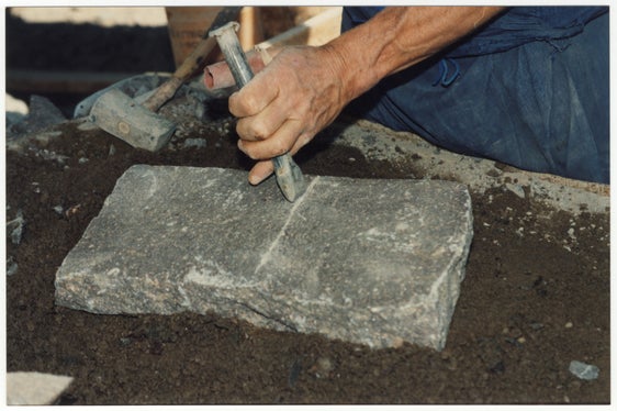 Mit Hammer und Meißel wird der Porphyr „formatiert“, sprich, zu einer Platte mit einer quadratischen Grundfläche gespalten: Die Arbeit wird auch heute noch vielfach in reiner Handarbeit durchgeführt. (Foto: Bruno Canali)