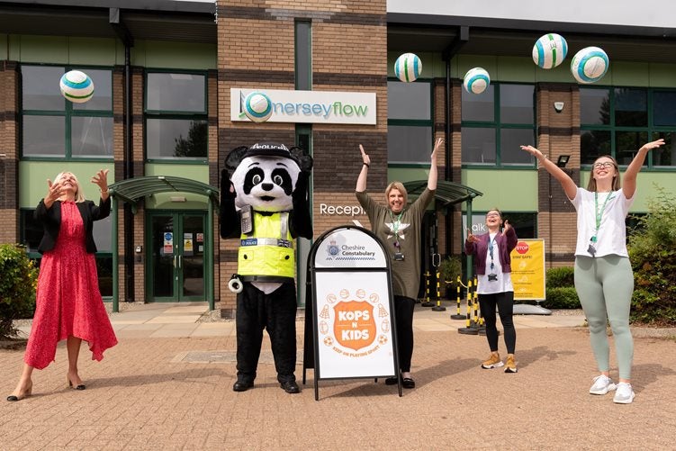 Group celebrating outside Merseyflow with a mascot and Kops 'n' Kids sign