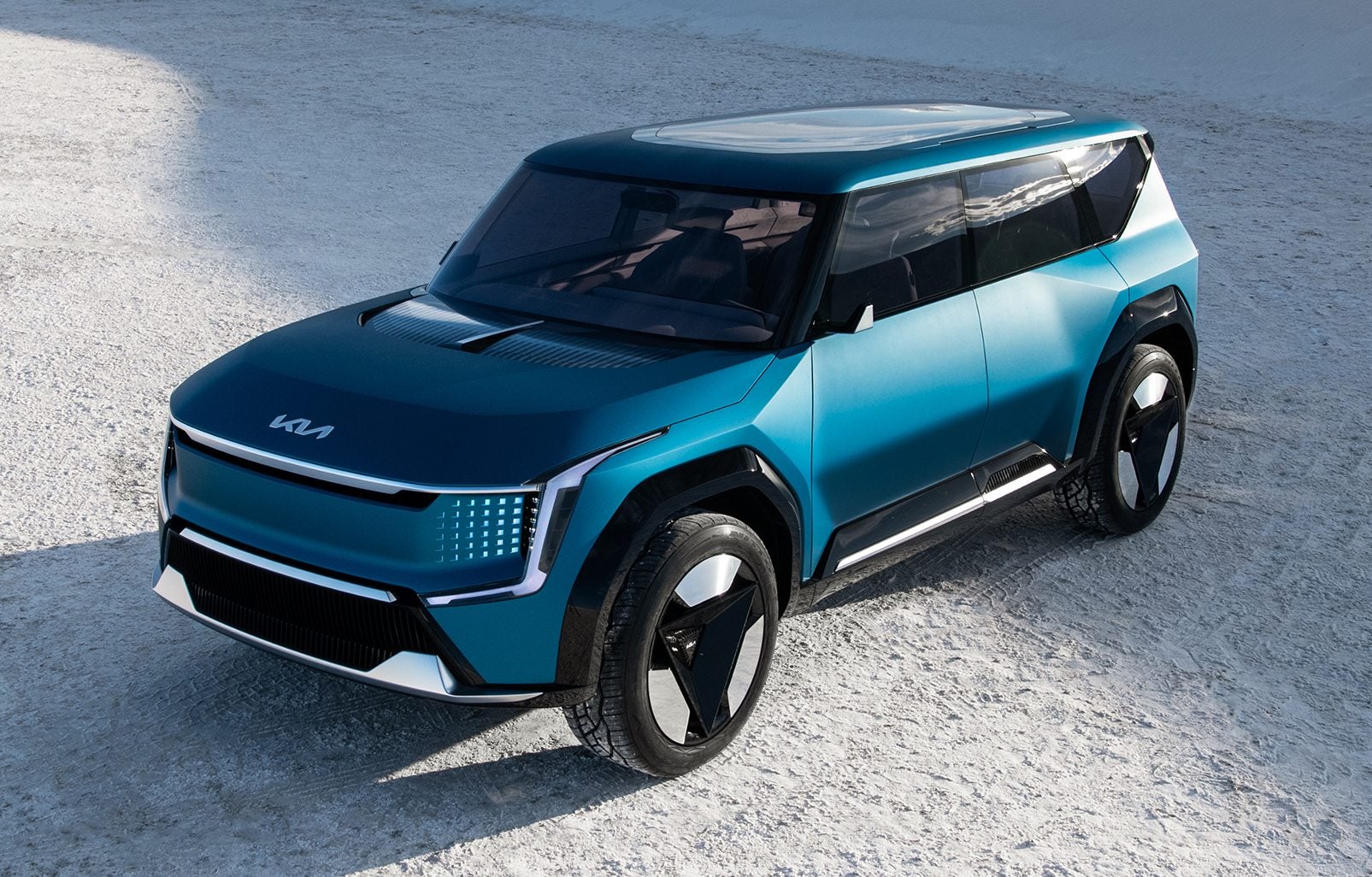Front-three quarter picture of a blue Kia EV9 parked on white sand