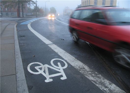 Cycle lane with a red car driving past 